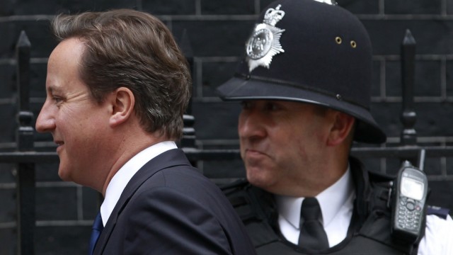Britain's Prime Minister Cameron walks past a police officer outside 10 Downing Street in London