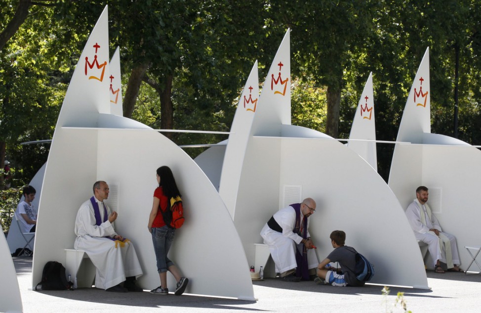 People confess at the confessional booths set up at Madrid's Retiro park on the first day of the World Youth Day meeting in Madrid