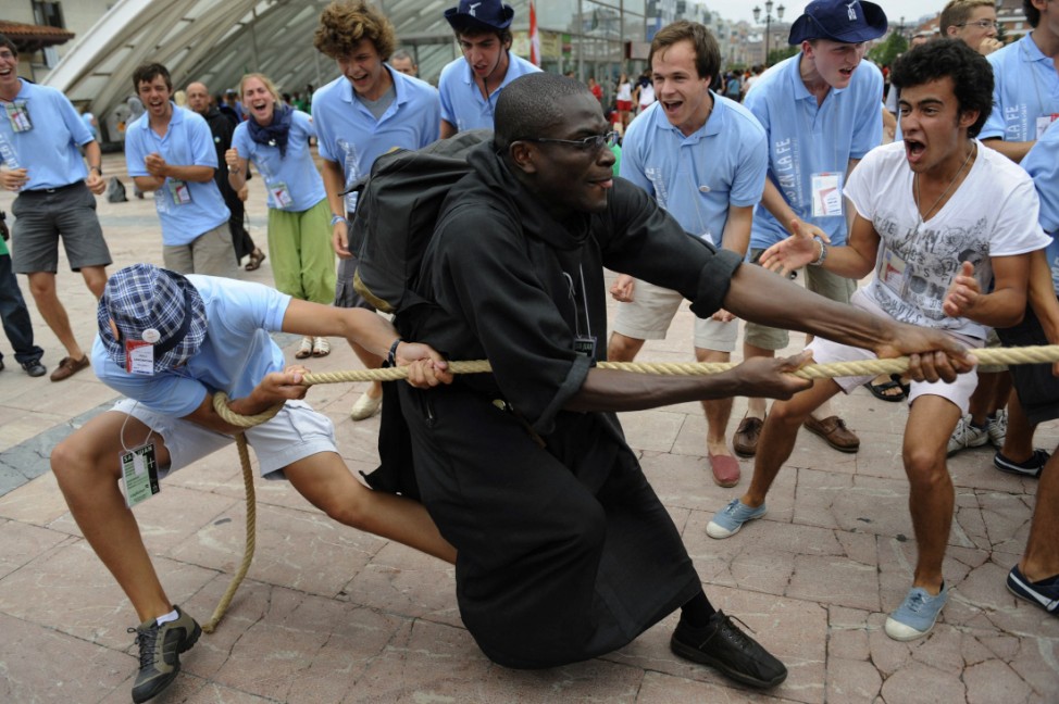 A French monk joins pilgrims in a game of tug of war in Oviedo