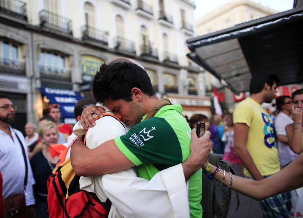 A volunteer embraces a monk during a demonstration against the cost of the papal visit in Madrid