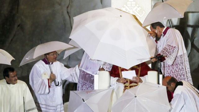 Unwetter beim Weltjugendtag: Schlechtes Wetter in der spanischen Hauptstadt: Priester versuchen, Papst Benedikt XVI. vor den heftigen Regengüssen zu schützen.