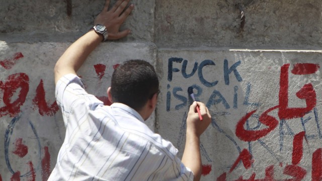 An Egyptian protester writes words against Israel during a protest in front of the Israeli embassy in Cair