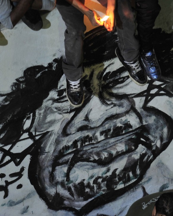 A cariacature of Libya's leader Muammar Gaddafi is seen as people gather near the courthouse in Benghazi