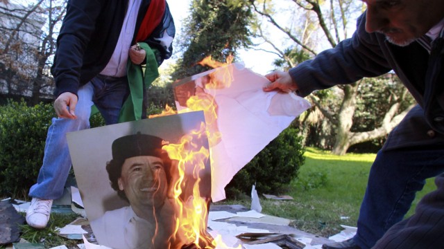 Employees of the Libyan Embassy burn a portrait of Gaddafi in Buenos Aires