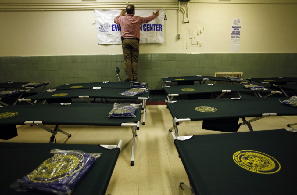 A volunteer puts up a sign in a shelter center at Newcomers High School in  Queens