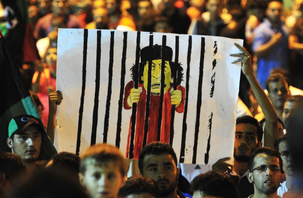 Men hold a cartoon of Libyan leader Muammar Gaddafi in Benghazi to celebrate the entry of rebel fighters into Tripoli.