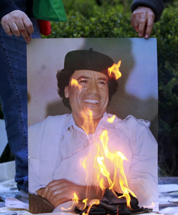 Employees of Libya's Embassy burn a portrait of Gaddafi in Buenos Aires
