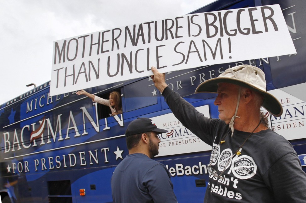 An activist holds a sign up as U.S. Republican presidential candidate and Minnesota Congresswoman Bachmann waves to a crowd from her campaign bus