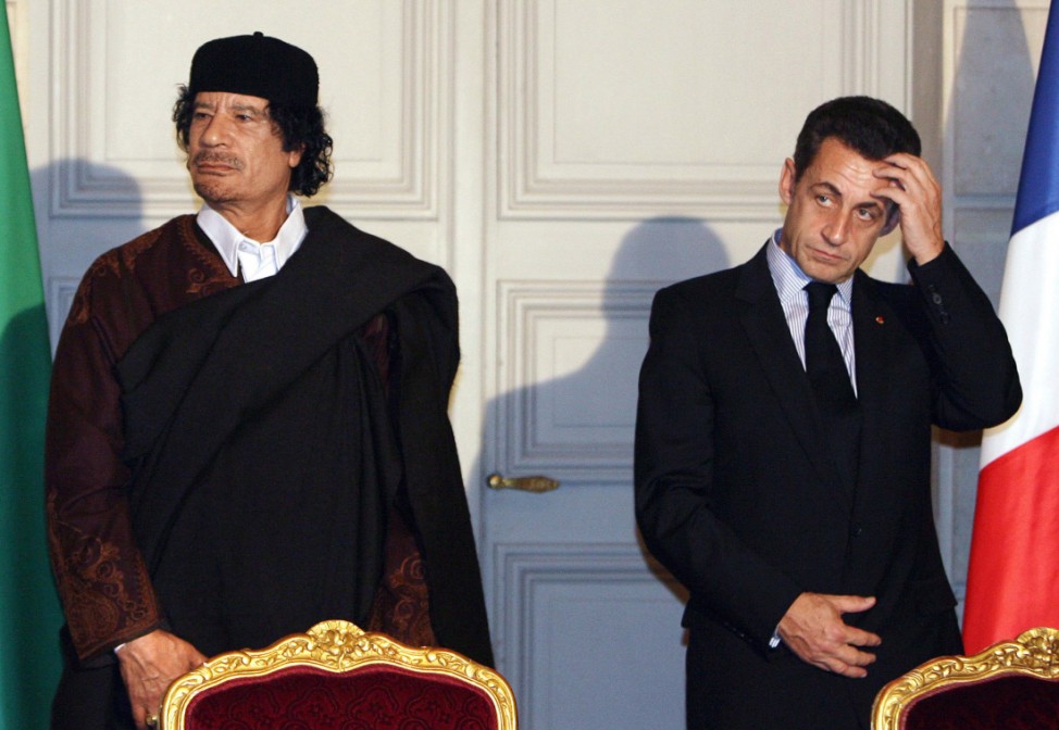 France's President Nicolas Sarkozy and Libyan leader Muammar Gaddafi leave the room after the signature of 10 billion euros of trade contracts in Paris