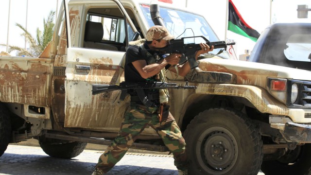 A rebel fighter fires his machine gun towards a sniper from a hotel where foreign journalists are staying at in Tripoli
