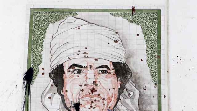 A bullet-riddled portrait of Muammar Gaddafi is seen on the wall of a building in Tripoli