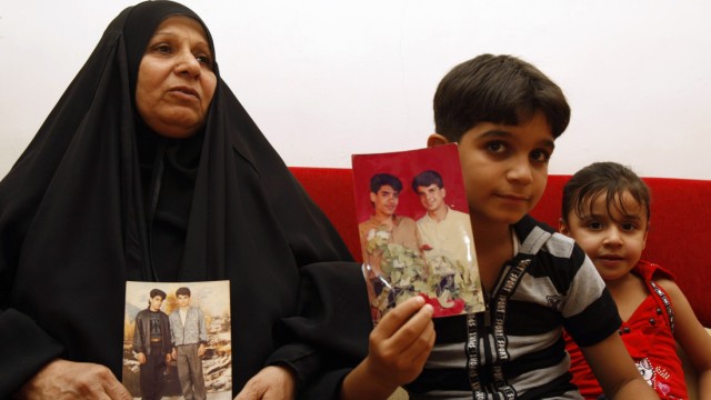 The mother and son of Baha Mousa (R in the picture), an Iraqi hotel receptionist who was kicked and beaten to death whilst in British Army custody, hold pictures of him at their house in Basra