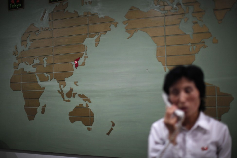 A world map with the Korea peninsula marked in red is seen as a hotel receptionist talks on the phone in Rason city