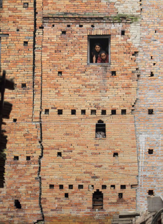 Women look out from the window of a quake-damaged house in Bhaktapur