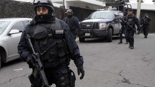 Federal police officers block access to a street during a raid at a house in Mexico City