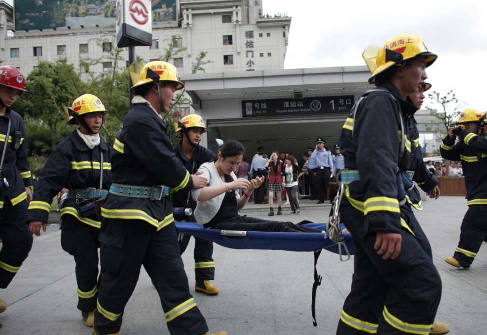 An injured woman is evacuated by rescue workers outside Yu Yuan Garden station in Shanghai