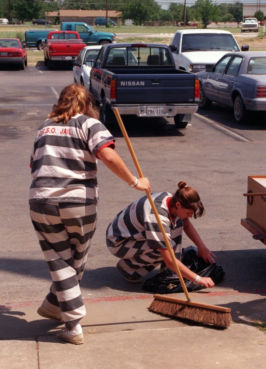 Zwei weibliche Strafgefangene fegen die Straße