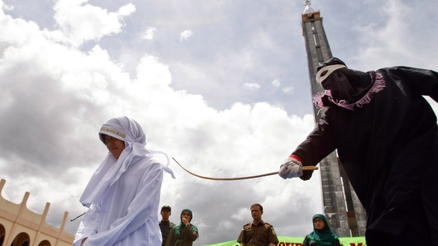 Arabischer Aufstand und Scharia: Ein Maskierter peitscht eine Frau in Indonesien aus: Allein mit solchen Strafen verbindet man die Scharia häufig im Westen. Muslime verstehen die Scharia hingegen als Aufruf zu moralischem Verhalten