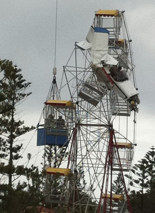 A rescue crew tries to reach an ultra-light plane after it crashed into a ferris wheel at a fair near Taree
