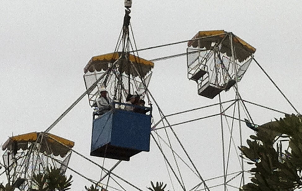 Emergency personnel rescue two children trapped in a ferris wheel after an ultra-light plane crashed into it at a local fair near Taree