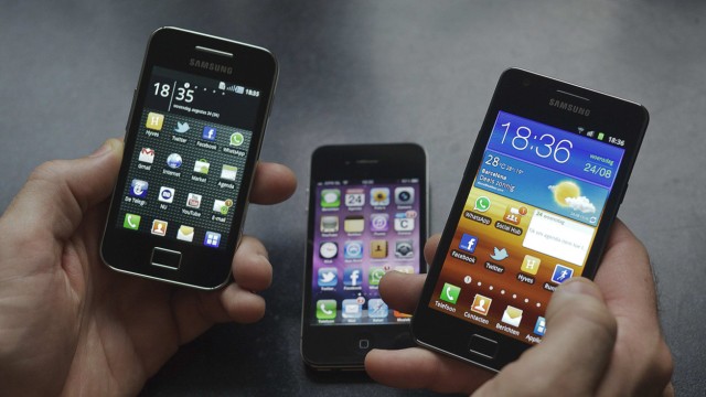 File photo of man holding a Samsung S II and Samsung Ace smartphones next to an Apple iPhone 4 in Houten