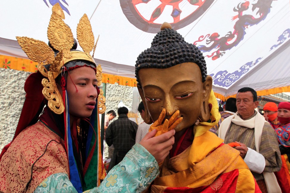 Traditional Bhutanese dancer dressed up like a Budha ( R) wit