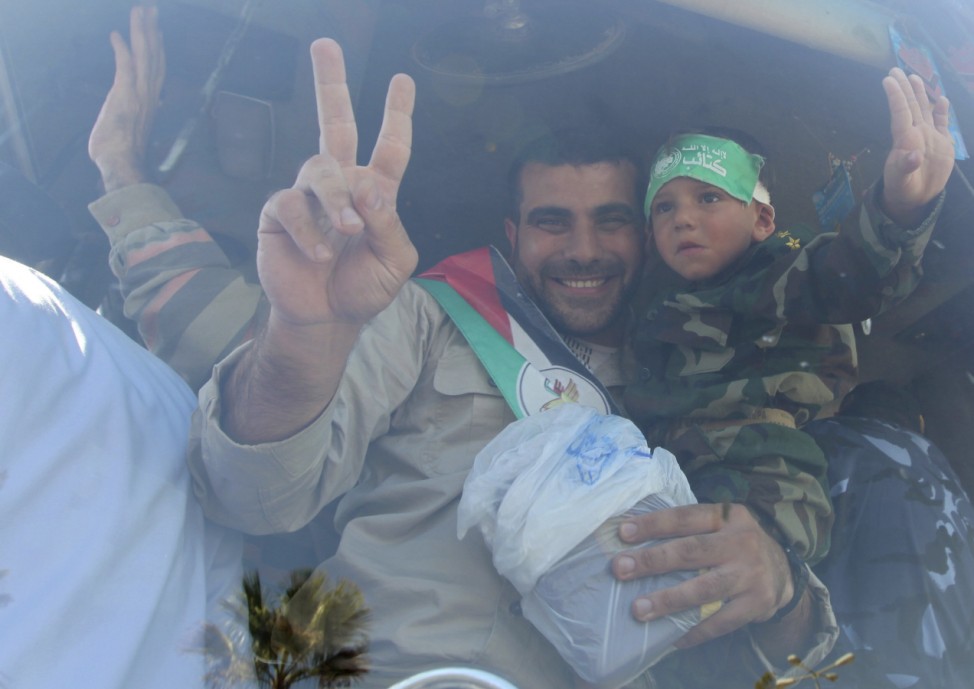 A Palestinian prisoner gestures as he holds his son after arriving at the Rafah crossing