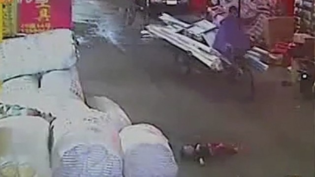 Schockierendes Unfallvideo aus China: Minutenlang liegt die kleine Yue Yue (vorne im Bild) schwerverletzt und jammernd auf dem Boden, ohne dass dem zweijährigen Mädchen aus China einer der Passanten in der Nähe zur Hilfe kommt.