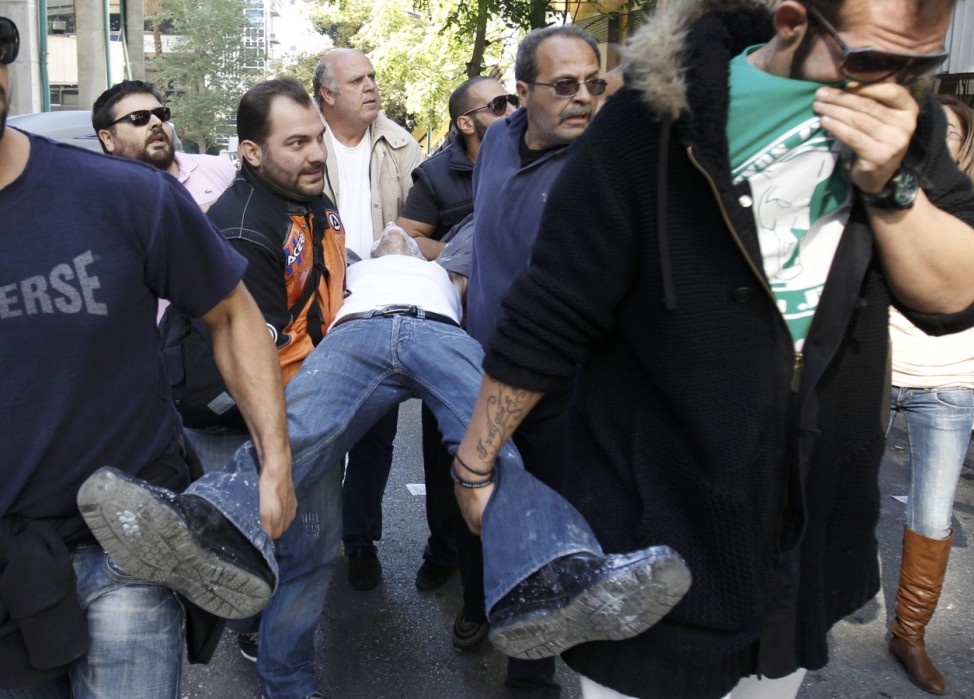 An injured anti-austerity demonstrator is carried to safety during clashes with riot police in Athens' Syntagma square