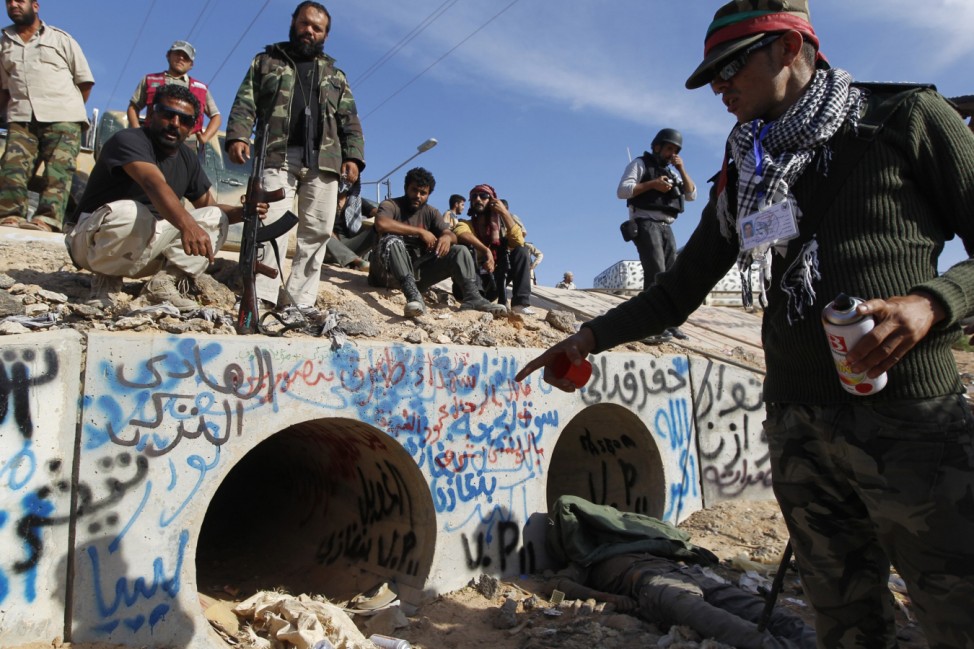 An anti-Gaddafi fighter points at the drain where Muammar Gaddafi was hiding before he was captured in Sirte