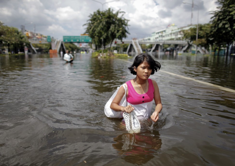 A girl holds her shoes as she makes her way out of a flooded area in central Bangkok