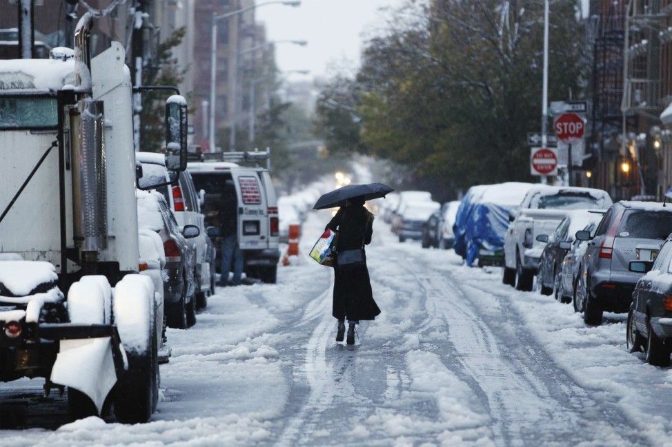A woman walks down a snow-covered street during an early snow storm in New York