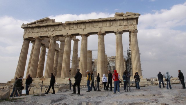 Tourists walk in front of the Parthenon temple at the archaeological site of the Acropolis hill in Athens