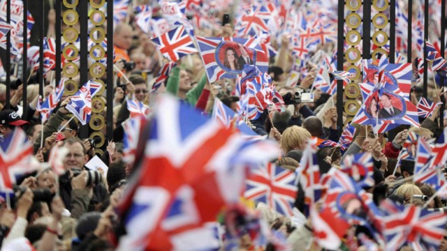 People wave British flags outside Buckingham Palace during the wedding of Britain's Prince William and Kate Middleton at Westminister Abbey, in central London