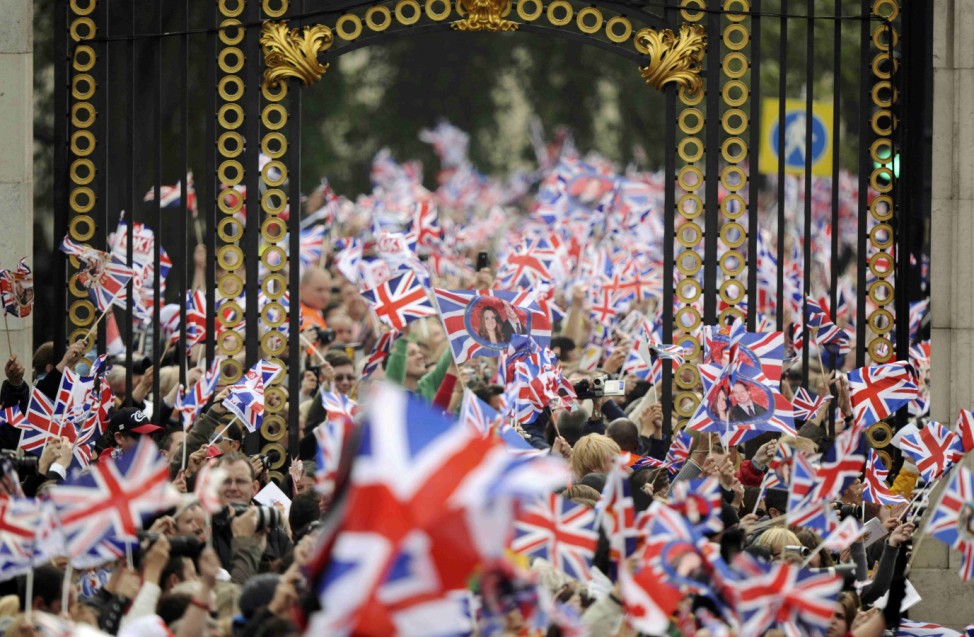 People wave British flags outside Buckingham Palace during the wedding of Britain's Prince William and Kate Middleton at Westminister Abbey, in central London