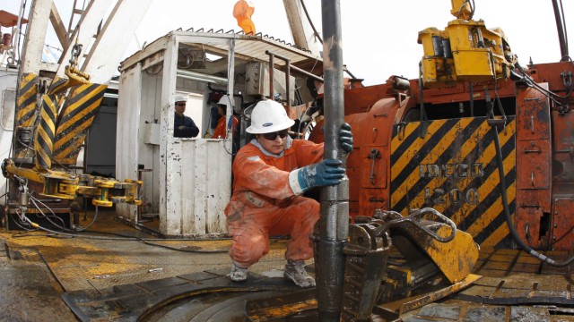 A worker manoeuvres an exploration drill bit at an oil and gas drilling rig in the Patagonian province of Neuquen