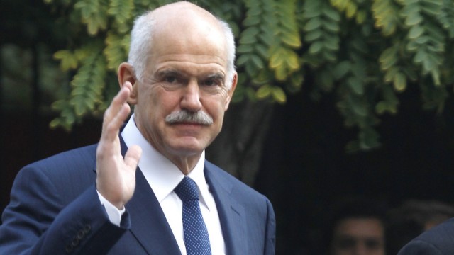 Outgoing Greek Prime Minister George Papandreou waves at reporters as he walks towards the presidential palace in Athens