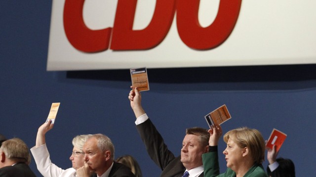German Chancellor Merkel holds up a voting card during CDU party convention in Leipzig
