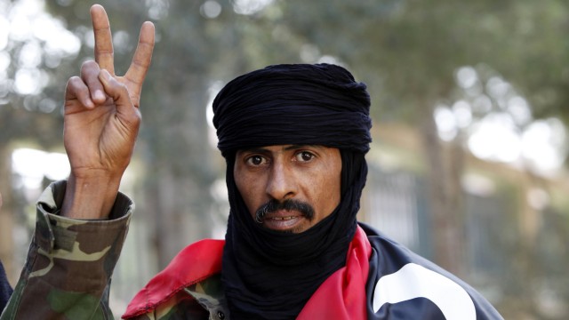 Yussef Saleh al-Hotmani gestures while wearing a Kingdom of Libya flag in Zintan