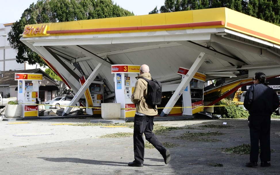 A man walks past a gasoline station that was damaged during a high wind storm in Pasadena, California