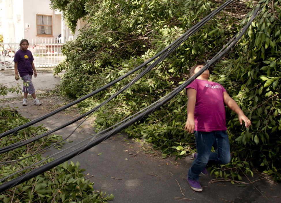 A girl ducks under a downed power line in the Highland Park neighborhood of Los Angeles