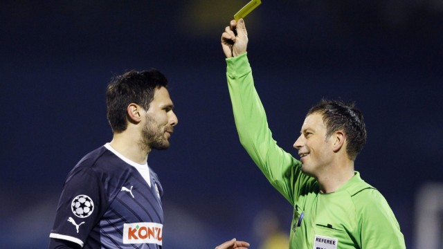 Referee Mark Clattenburg shows the yellow card to Jerko Leko of Dinamo Zagreb during their Champions League Group D soccer match against Lyon at Maksimir stadium in Zagreb