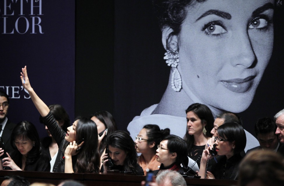 A phone bidder signals her bid near an image of Elizabeth Taylor during an auction of the late actress' jewelry, clothing, art and memorabilia in New York