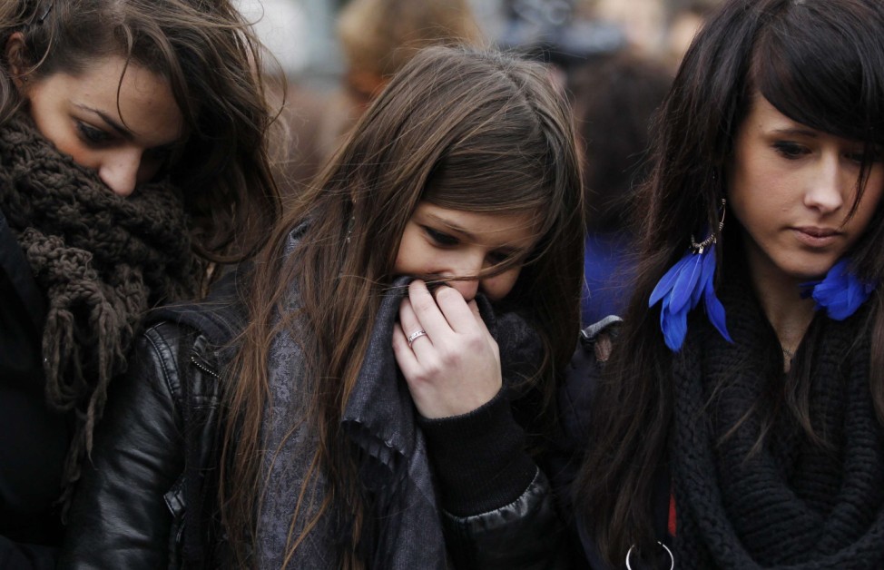 Women mourn as they stand near the site of a gun and grenade attack in central Liege