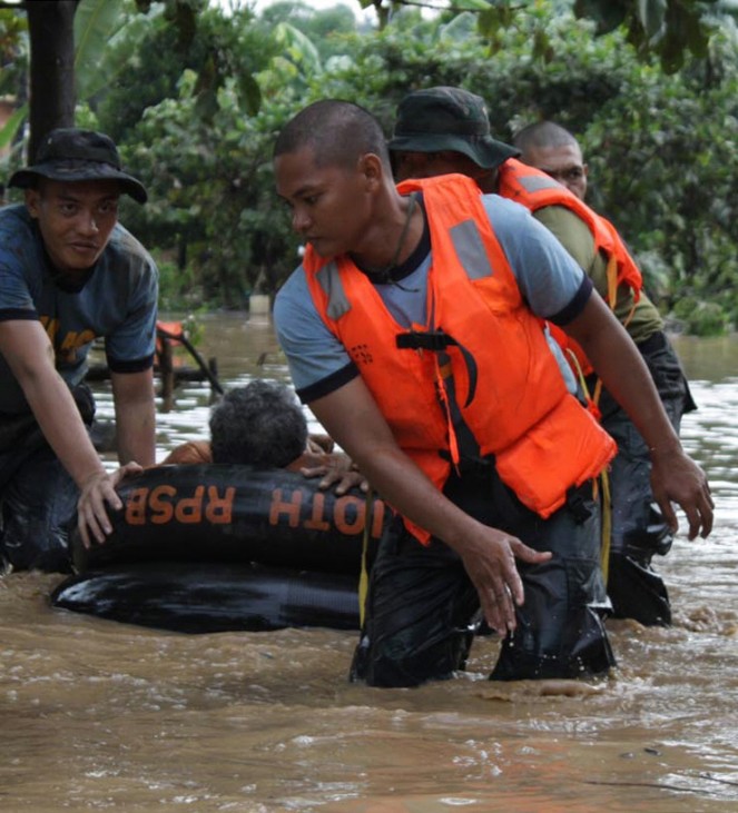 Philippine National Police rescuers use a rubber boat to evacuate a resident after flash floods brought by Typhoon Washi hit Macasandig town, Cagayan De Oro city