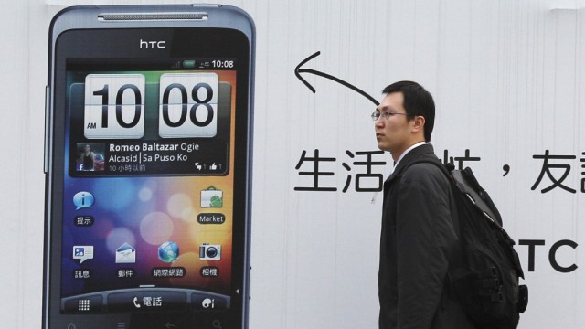 A man walks past a HTC advertisement in Taipei