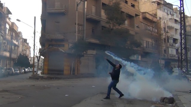 Erste Eindrücke der Beobachtermission in Syrien: Ein Demonstrant in der syrischen Stadt Homs wirft eine Tränengas-Granate zurück in Richtung der Sicherheitskräfte. Die Oppositionshochburg bildet das Zentrum der Proteste gegen Machthaber Assad - die Beobachter der Arabischen Liga sahen bei ihrem Besuch aber keinen Grund zur Besorgnis.