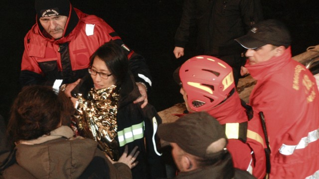 South Korean woman is helped after been rescued with her husband from Costa Concordia cruise as it ran aground off the west coast of Italy at Giglio island