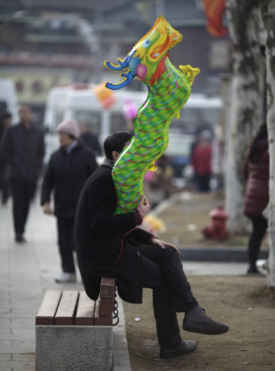 A man holds a dragon balloon outside Longhua Buddhist Temple on the first day of the Chinese Lunar New Year in Shanghai