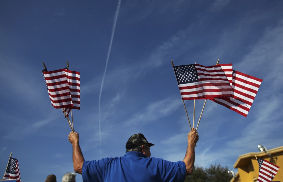 A man waves U.S. flags outside an event for U.S. Republican presidential candidate and former Speaker of the House Gingrich in Orlando, Florida